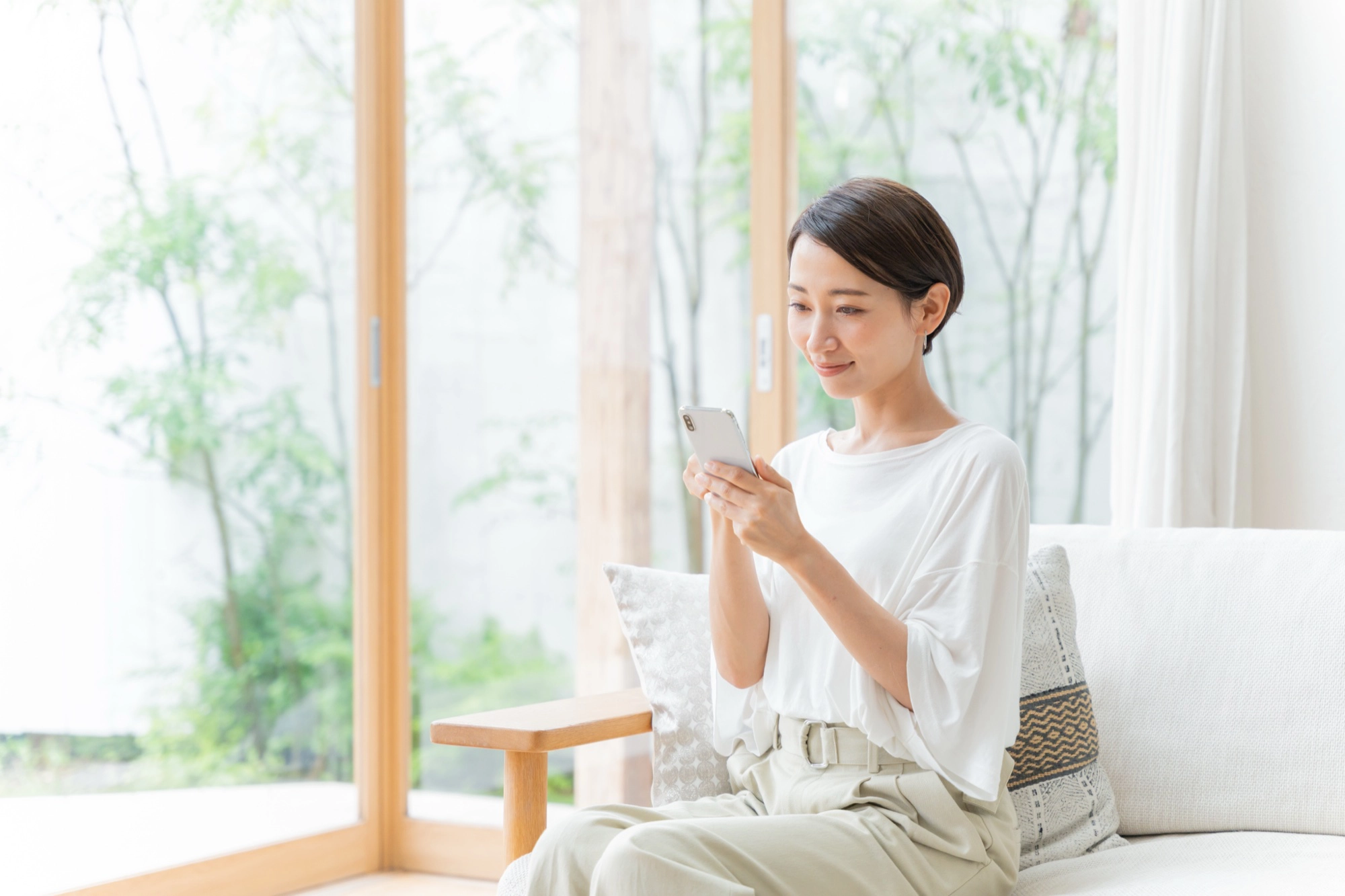ソファでスマートフォンを操作する女性