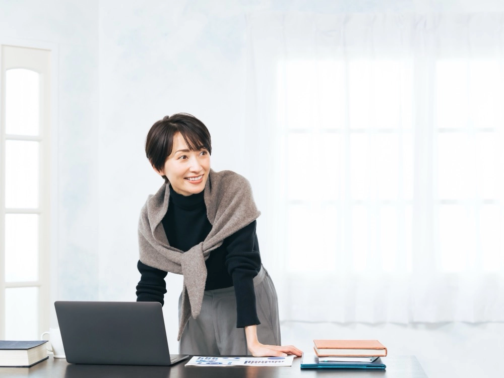 ノートパソコンの前で微笑む女性